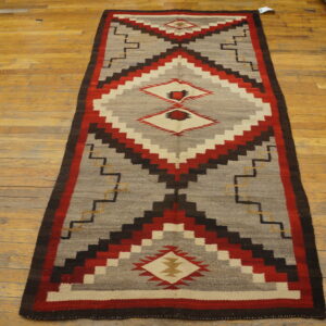 Flatweave runner in red, gray, brown, and cream features large stepped diamond designs on wood flooring.