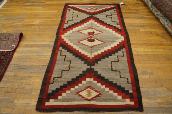 Flatweave runner in red, gray, brown, and cream features large stepped diamond designs on wood flooring.