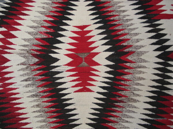 Flatweave rug featuring serrated diamond patterns in red, black, cream, and heathered gray colors.