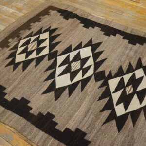 Low-pile brown and cream geometric rug with dark stepped borders lying on distressed hardwood.