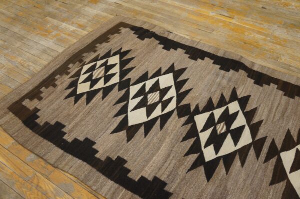 Earthy runner rug featuring dark brown and cream stepped geometric diamonds on distressed wood flooring.