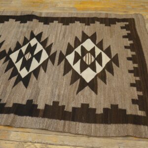 Brown, dark brown, and cream geometric rug featuring large central diamonds laid on a yellow wood floor.