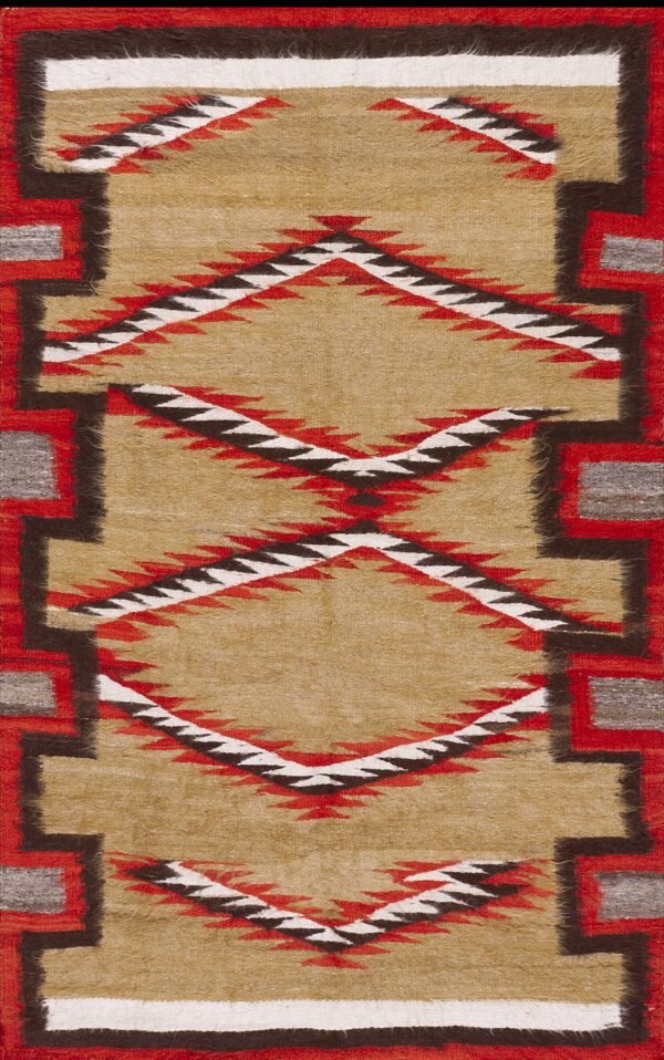 Tan low-pile rug featuring red, black, and white sawtooth diamonds and stepped geometric borders.