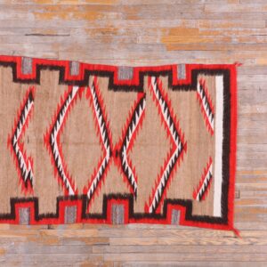 Tan, red, black, and white geometric rug with stepped border and diamonds on distressed hardwood floor.