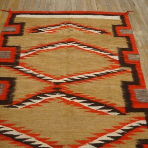Tan, red, and dark brown serrated diamond runner rug displayed against distressed wide plank wood.