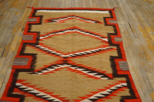 Tan, red, and dark brown serrated diamond runner rug displayed against distressed wide plank wood.