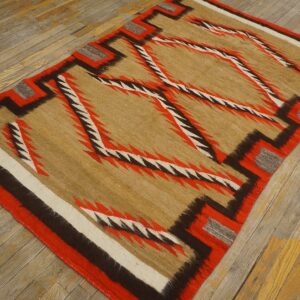 Geometric flatweave rug featuring jagged red, brown, and tan lines, placed on distressed wood planks.