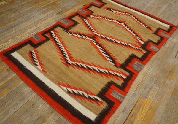 Geometric flatweave rug featuring jagged red, brown, and tan lines, placed on distressed wood planks.