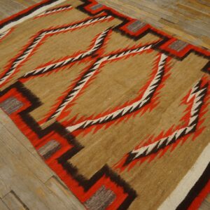 Tan, red, and brown flatwoven rug featuring large jagged geometric diamonds on distressed wood floor.