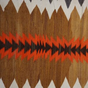 Coarse flatweave rug with brown, white, rust, and black zigzag and sawtooth patterns.