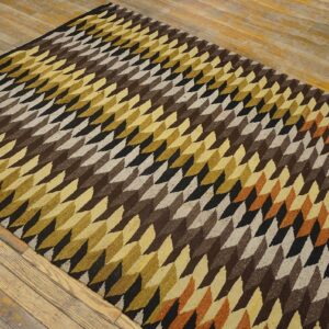 Low-pile rug with geometric brown, gold, black, and beige diamond patterns on wood flooring.