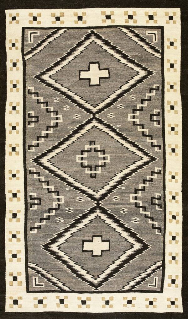 Geometric flatweave rug in gray, black, cream, and tan, featuring bold diamond motifs.