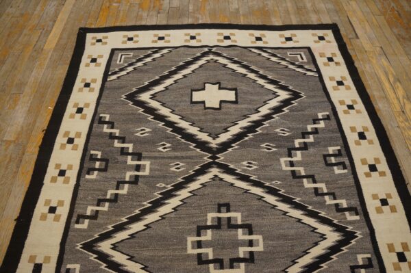 Geometric flatweave rug in gray, black, and cream colors laid on aged yellow wood floors.