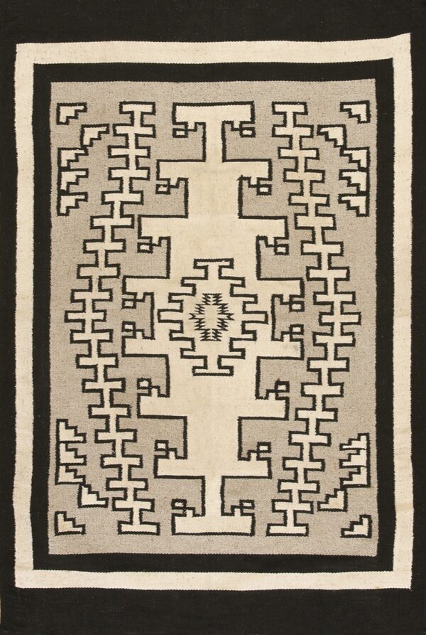 Black, gray, and cream flat-weave rug with interlocking geometric patterns and a large central cross motif.