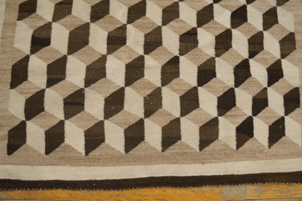 Geometric flatweave rug featuring interlocking cubic designs in shades of brown, taupe, and natural beige.