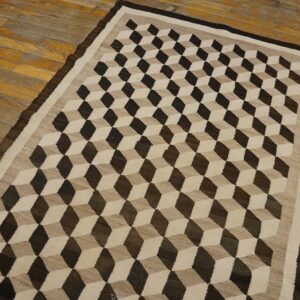 Flatwoven rug in dark brown, tan, and beige with a geometric cube pattern on distressed wood floor.