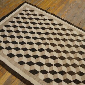 Brown and cream rug featuring a 3D cube optical pattern on wide, rustic wood flooring.
