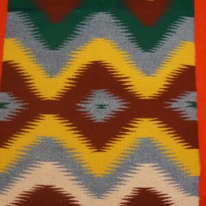 Multicolored flatweave runner featuring zigzag designs in brown, gold, gray, and green on distressed wood planks.