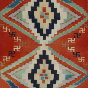 A flatweave rug features orange-red, navy, cream, and teal stepped diamond geometric patterns.