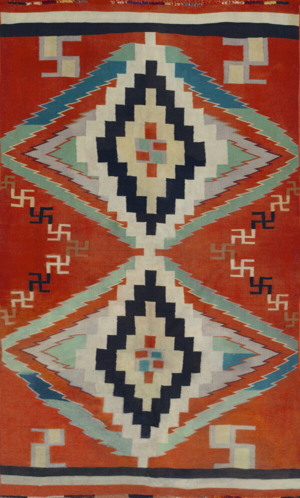 A flatweave rug features orange-red, navy, cream, and teal stepped diamond geometric patterns.