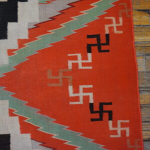 Red, black, and white flatweave rug with geometric symbols and zigzag patterns on distressed wood.
