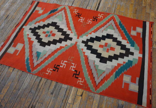 Orange flatweave rug displays large black, white, and mint geometric diamonds on rustic wooden floorboards.