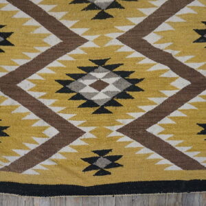 Mustard yellow, brown, gray, and black diamond-patterned flat-woven rug on wood flooring.