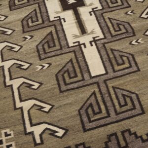 Low-pile rug detail showing geometric interlocking patterns in khaki, cream, and shades of brown.