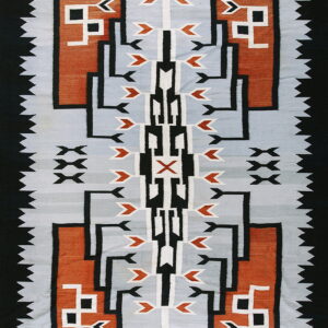 Geometric textile in gray, rust, black, and white featuring stepped patterns and a serrated black edge.