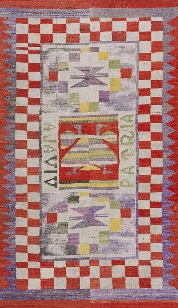 Flatwoven rug with red and cream checkered borders, geometric motifs, and the words "alavia patria. "