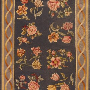 Low-pile rug with a charcoal field, pink and gold floral motifs, and a serpentine gray and yellow border.