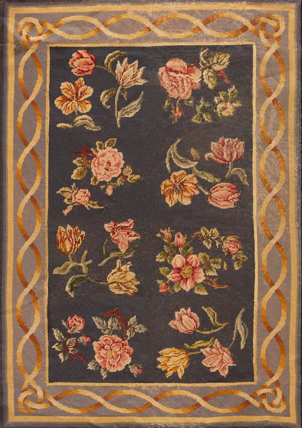 Low-pile rug with a charcoal field, pink and gold floral motifs, and a serpentine gray and yellow border.