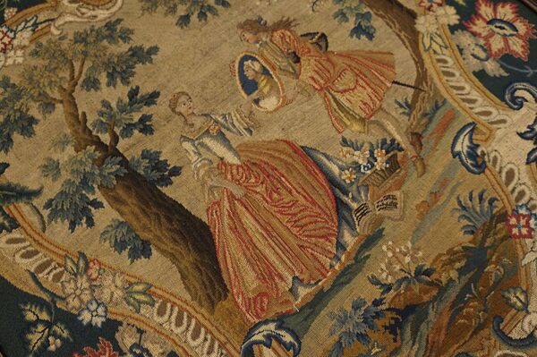 Detailed flat-woven rug showing figures and trees, utilizing blue, rust, gold, and green colors.