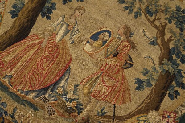 Low-pile tapestry depicting a tan, gold, and red figural scene with brown trees and blue-green foliage.