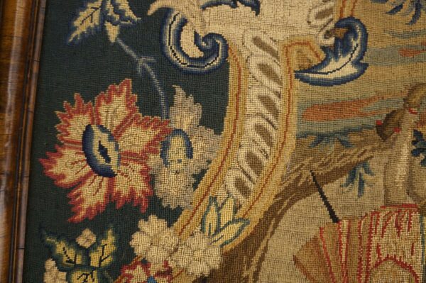 Framed low-pile textile featuring detailed gold, red, and blue floral scrollwork on a dark green background.