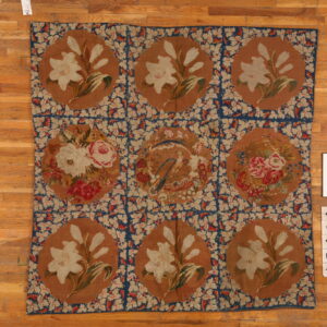 Low pile rug featuring nine brown medallions with floral and bird motifs connected by a blue lattice pattern.