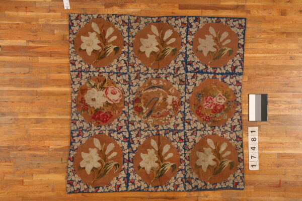 Low pile rug featuring nine brown medallions with floral and bird motifs connected by a blue lattice pattern.