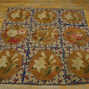 Floral tapestry rug with nine medallions featuring lilies and roses, set on distressed wooden planks.
