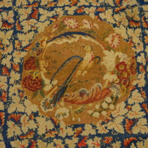 Ornate rug detail in blue, cream, gold, and red, featuring floral vines and a medallion with bird-like shapes.