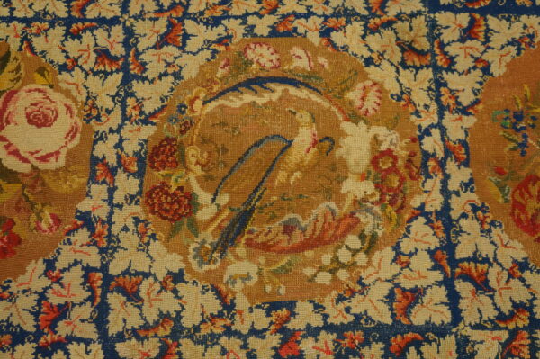 Ornate rug detail in blue, cream, gold, and red, featuring floral vines and a medallion with bird-like shapes.