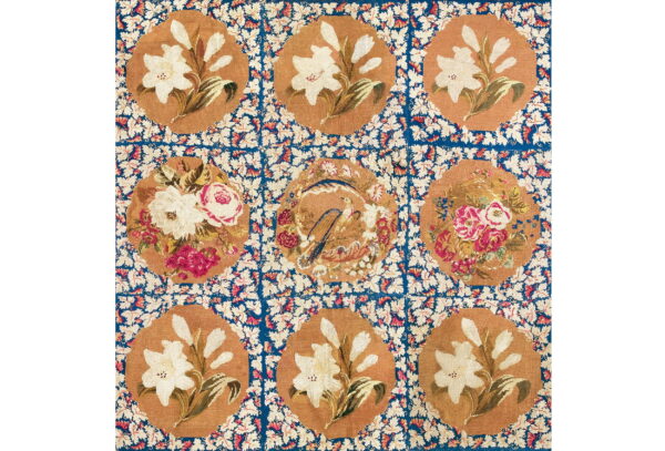 Nine floral medallions in tan and off-white set within a vibrant blue, leaf-patterned grid.