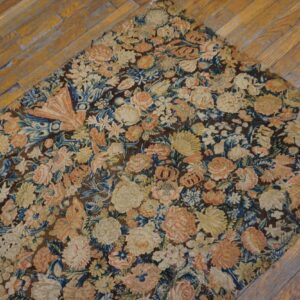 Low-pile rug with dense pink, cream, and blue floral motifs on a brown field over wood flooring.