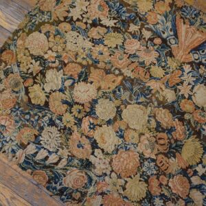 Low-pile tapestry-style rug with intricate floral designs in blue, peach, and cream on wood floors.