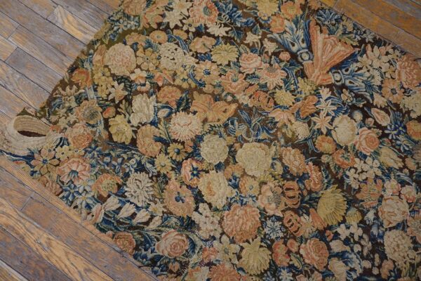 Low-pile tapestry-style rug with intricate floral designs in blue, peach, and cream on wood floors.