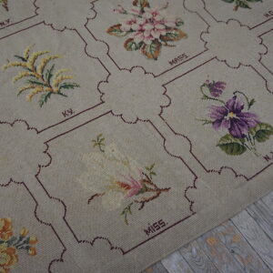 Beige low-pile rug featuring framed floral tapestry squares rests on distressed gray wood flooring.