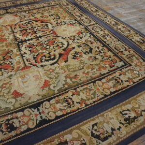 Ornate floral and scroll flatweave rug featuring black, olive, red, and tan colors, bordered in solid navy blue.
