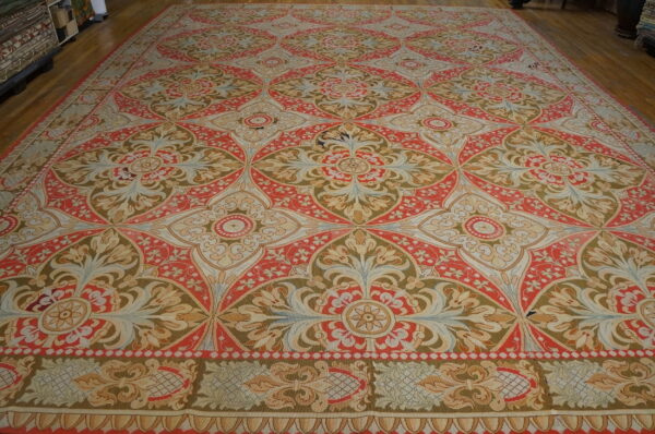 Large, low-pile rug with repeating coral, tan, and olive medallions covering a wooden floor.