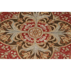 Symmetrical, low-pile rug pattern in deep red, dark brown, and beige with intricate foliate details.