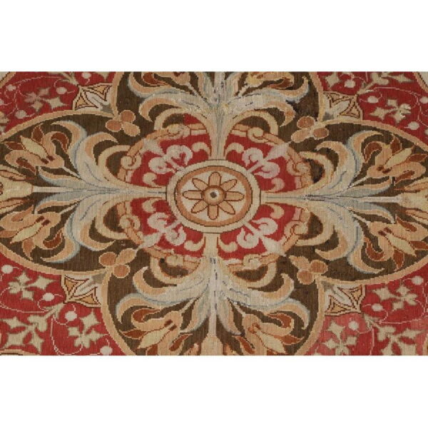 Symmetrical, low-pile rug pattern in deep red, dark brown, and beige with intricate foliate details.