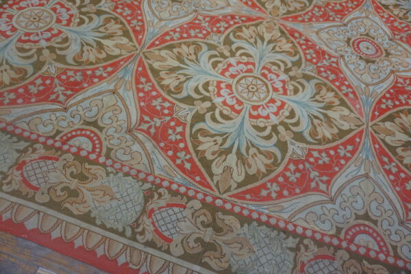 Flat-woven rug displaying large, detailed medallions in coral red, olive green, cream, and blue on a wood floor.